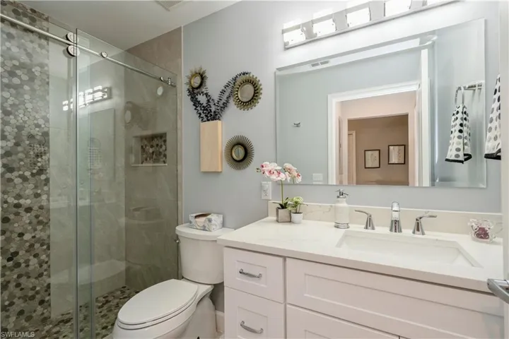 Bathroom with a shower with door, toilet, and vanity