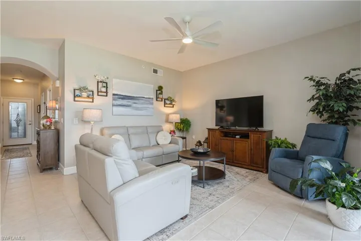 Living room with ceiling fan and light tile patterned flooring