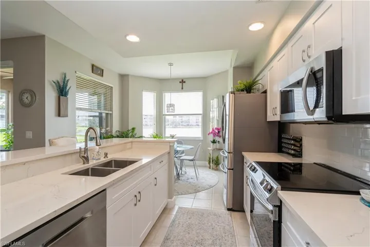 Kitchen featuring sink, white cabinets, appliances with stainless steel finishes, and light tile patterned floors