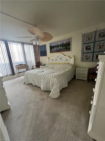 Bedroom with ceiling fan, dark colored carpet, and a textured ceiling
