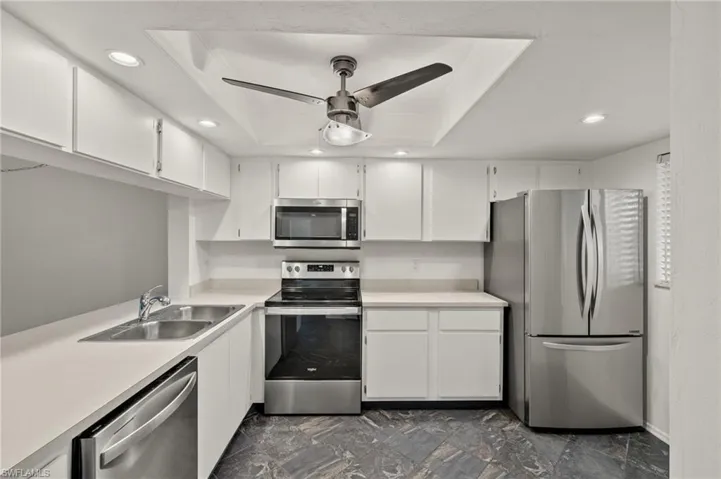 Kitchen with sink, white cabinets, a tray ceiling, and stainless steel appliances