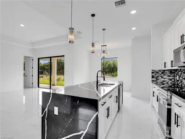 Kitchen with hanging light fixtures, recessed lighting, white cabinetry, stainless steel appliances, and tasteful backsplash