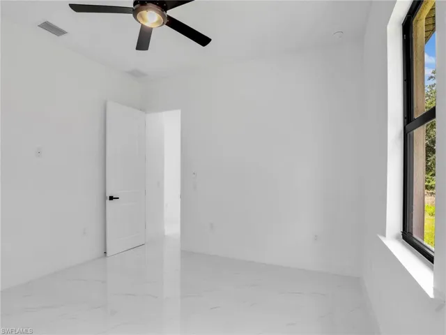 Empty room with light marble finish floors and ceiling fan