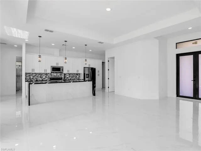 Unfurnished living room featuring recessed lighting, light marble finish floors, and a raised ceiling