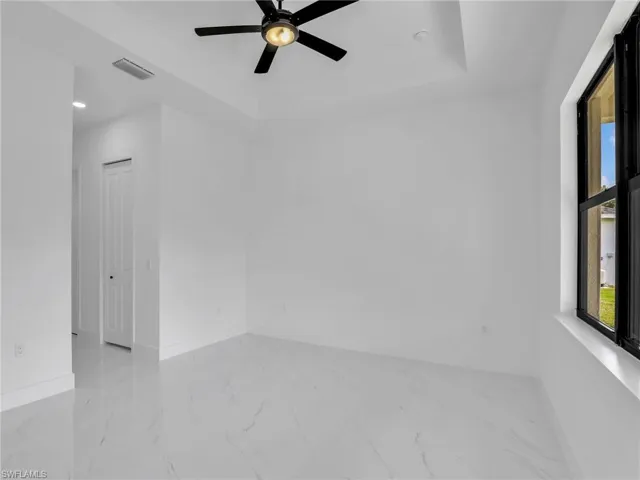 Unfurnished room featuring a tray ceiling, light marble finish floors, a ceiling fan, and recessed lighting