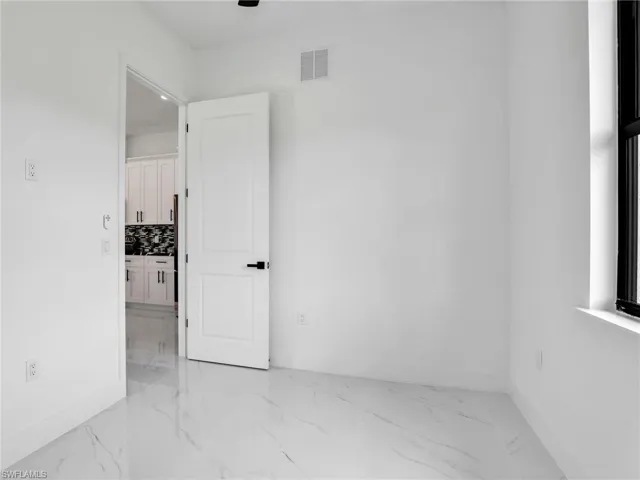 Spare room featuring light marble finish floors and baseboards
