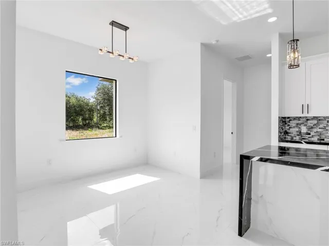 Unfurnished dining area with a chandelier, light marble finish flooring, and recessed lighting