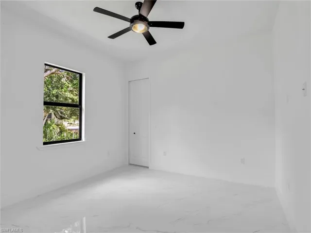 Unfurnished room with light marble finish floors and a ceiling fan