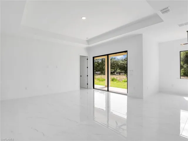 Unfurnished room featuring a raised ceiling, light marble finish flooring, and recessed lighting
