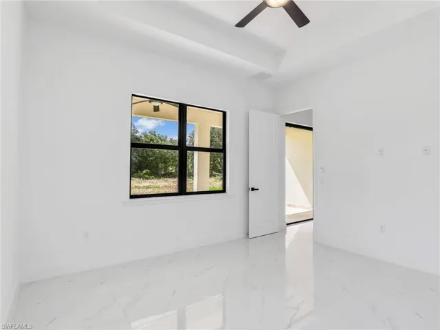 Empty room featuring light marble finish flooring and ceiling fan