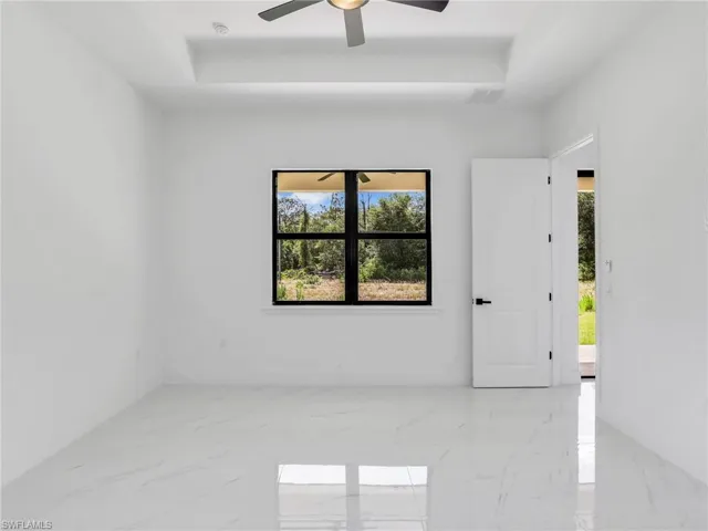 Empty room featuring light marble finish flooring, a raised ceiling, and plenty of natural light