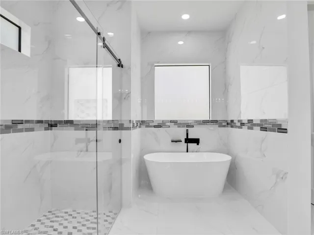 Bathroom featuring a soaking tub, a marble finish shower, marble tiled floors, and recessed lighting