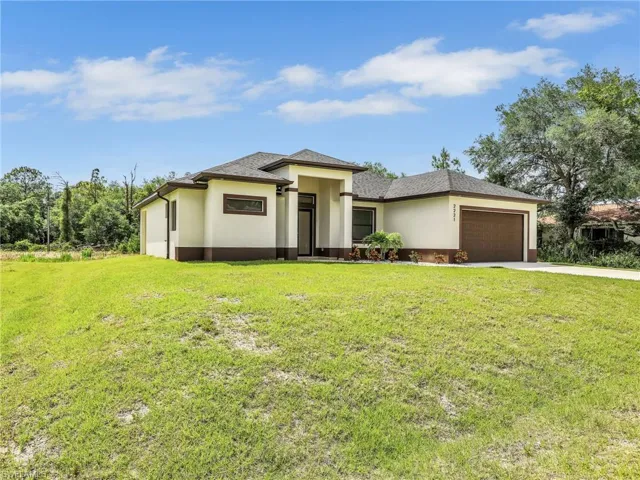 Prairie-style house featuring stucco siding, concrete driveway, a garage, and a front lawn
