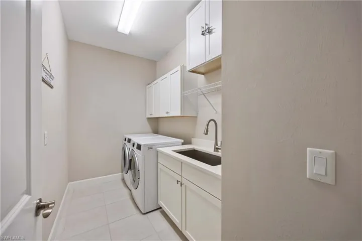 Laundry room featuring cabinet space, light tile patterned flooring, and separate washer and dryer