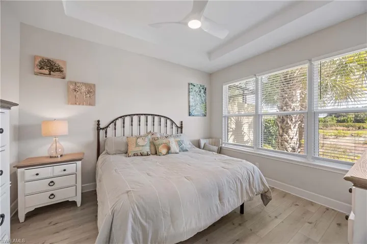 Bedroom featuring a raised ceiling, light wood finished floors, and ceiling fan
