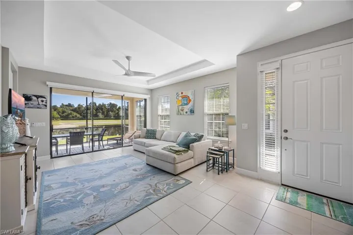 Living area with light tile patterned floors, a raised ceiling, plenty of natural light, and ceiling fan