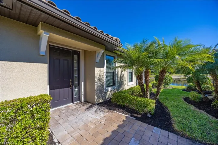 Entrance to property with stucco siding, a lawn, and a water view