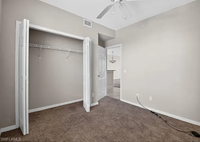 Unfurnished bedroom featuring carpet flooring, a closet, ceiling fan, and a chandelier