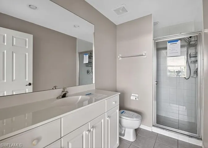 Full bath featuring light tile patterned floors, vanity, and a shower stall