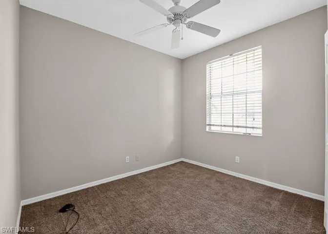 Carpeted empty room featuring baseboards and ceiling fan