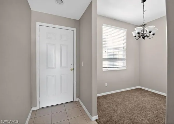 Entrance foyer featuring a chandelier, light carpet, and light tile patterned floors