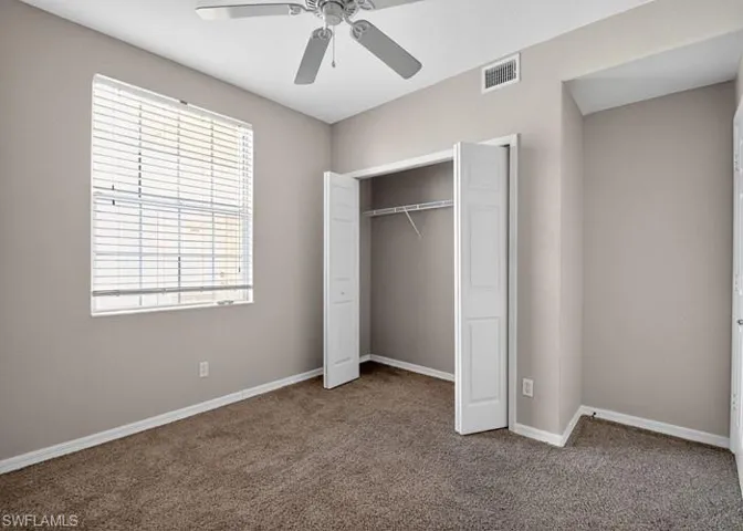 Unfurnished bedroom featuring carpet, a closet, and a ceiling fan