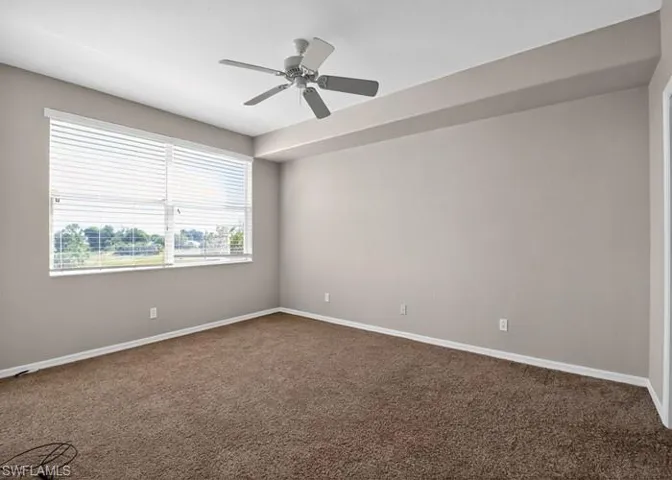 Empty room with dark colored carpet and ceiling fan