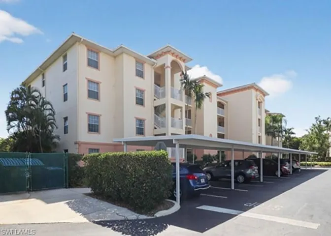 View of apartment building / complex featuring covered parking