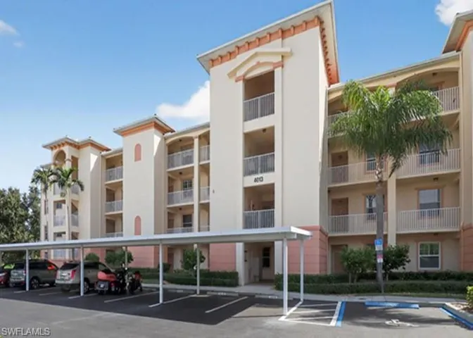 View of apartment building / complex featuring covered parking