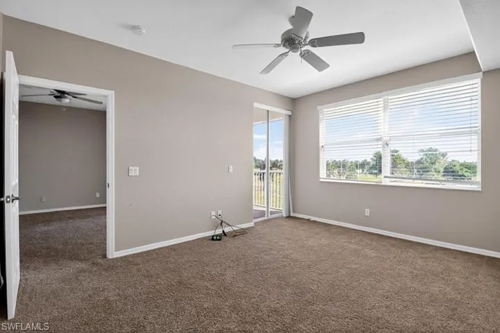 Empty room with a ceiling fan and dark carpet