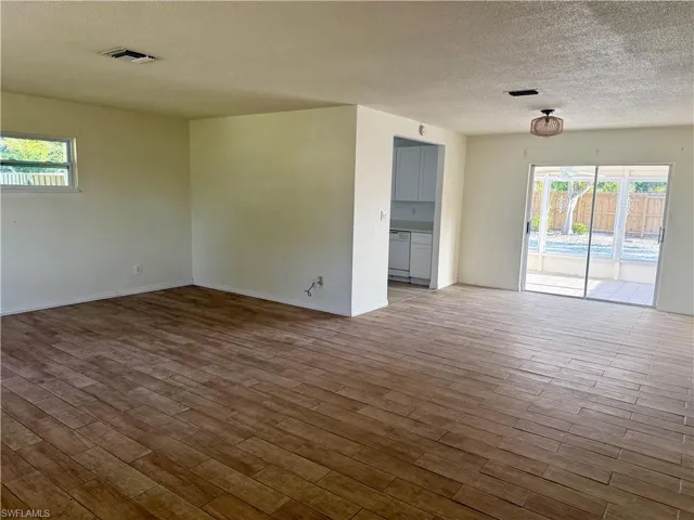 Empty room featuring baseboards, wood finished floors, a textured ceiling, and visible vents