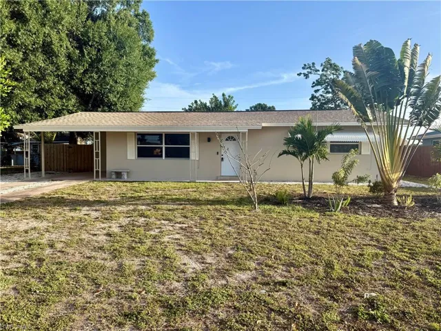 Ranch-style house featuring a front yard, an attached carport, stucco siding, and fence