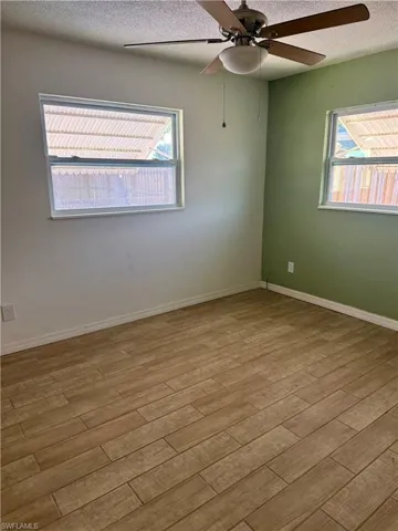 Unfurnished room with plenty of natural light, a ceiling fan, and wood finished floors