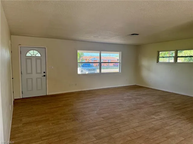 Foyer with wood finished floors, a textured ceiling, baseboards, and visible vents