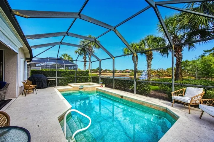 View of pool featuring a patio, a pool with connected hot tub, a grill, and glass enclosure