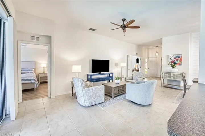 Living area with visible vents, vaulted ceiling, light tile patterned flooring, and ceiling fan