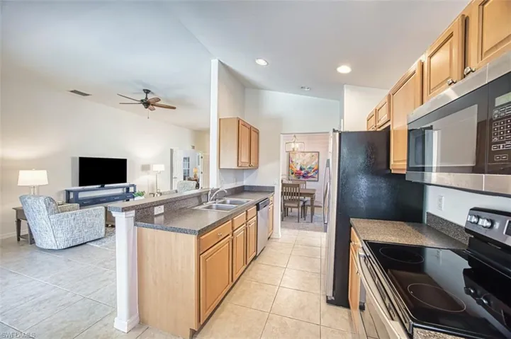 Kitchen with a peninsula, dark countertops, visible vents, stainless steel appliances, and a sink