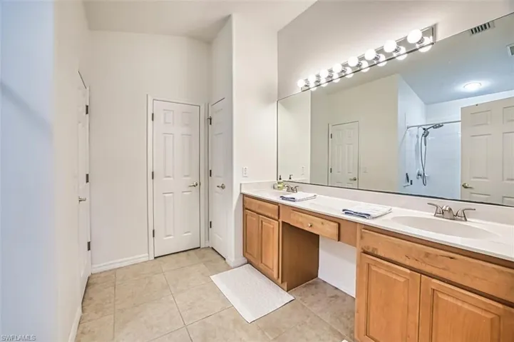 Bathroom with a stall shower, double vanity, a sink, and tile patterned flooring