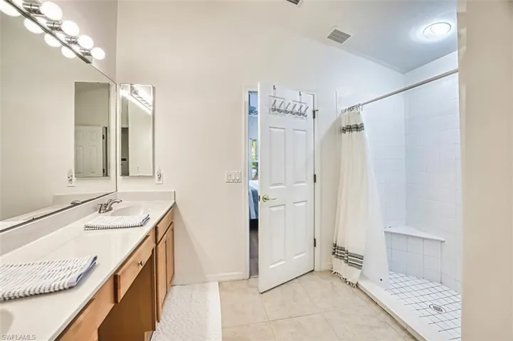 Ensuite bathroom featuring a sink, double vanity, tile patterned floors, ensuite bathroom, and a tile shower
