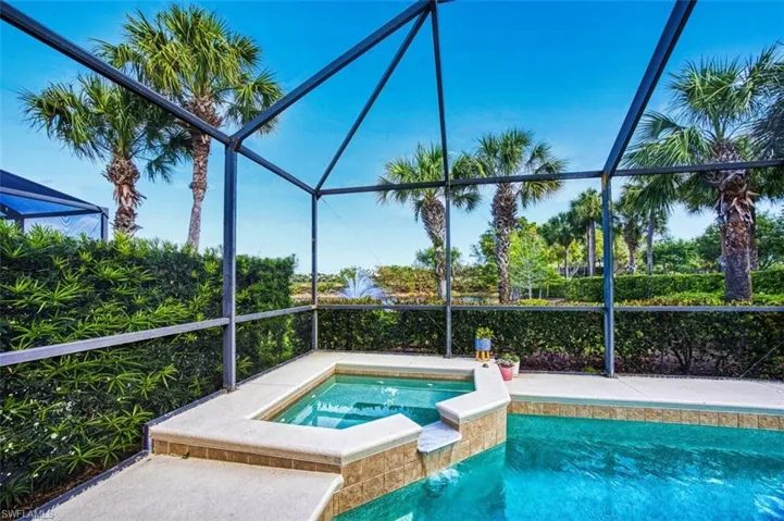 Outdoor pool featuring an in ground hot tub and glass enclosure