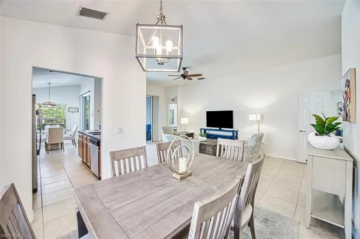Dining room featuring visible vents, a notable chandelier, light tile patterned flooring, and lofted ceiling