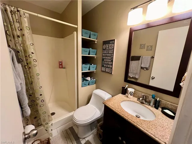 Bathroom with walk in shower, tile patterned floors, toilet, and vanity