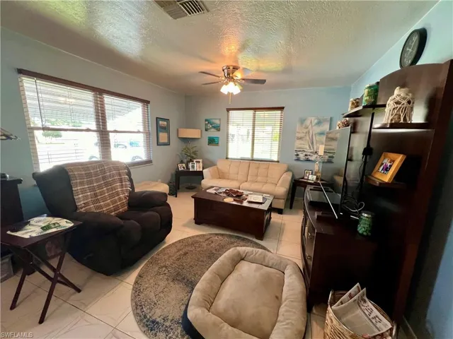 Living room with light tile patterned flooring, a textured ceiling, and ceiling fan