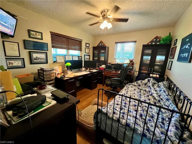 Bedroom with a textured ceiling, ceiling fan, and vinyl wood-type flooring