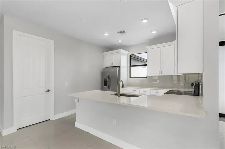 Kitchen with backsplash, sink, stainless steel fridge with ice dispenser, stove, and kitchen peninsula