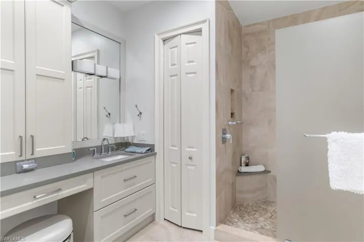 Bathroom with tile patterned flooring, a closet, tiled shower, and vanity