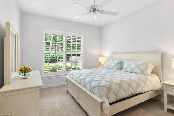 Bedroom featuring light colored carpet, ceiling fan, and baseboards