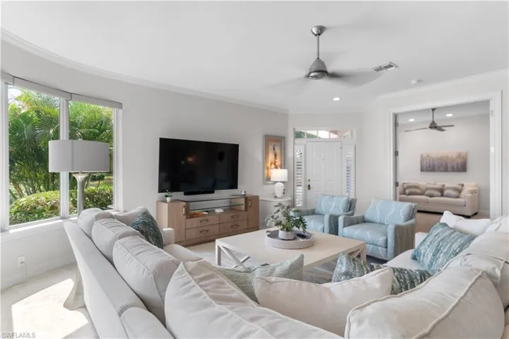 Living area with visible vents, crown molding, and ceiling fan