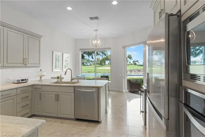 Kitchen with stainless steel appliances, light countertops, decorative backsplash, a sink, and a peninsula