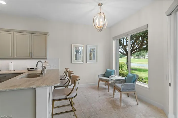 Kitchen featuring baseboards, gray cabinetry, decorative backsplash, a sink, and a kitchen breakfast bar